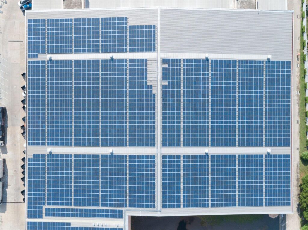 Aerial view of solar panels installed across a large factory rooftop